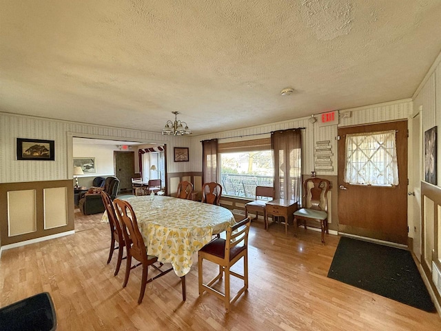 637 N Wright Rd, Janesville, WI 53546 - dining space featuring a textured ceiling, light wood-style floors, a chandelier, plenty of natural light, and a wainscoted wall