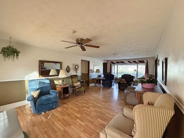 living room with ceiling fan, a textured ceiling, and light hardwood / wood-style flooring