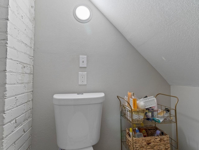 bathroom with toilet and lofted ceiling