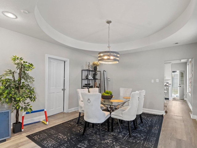 dining area with a raised ceiling, hardwood / wood-style floors, and a chandelier