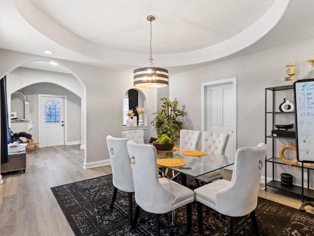 dining space featuring hardwood / wood-style floors, a raised ceiling, and a chandelier