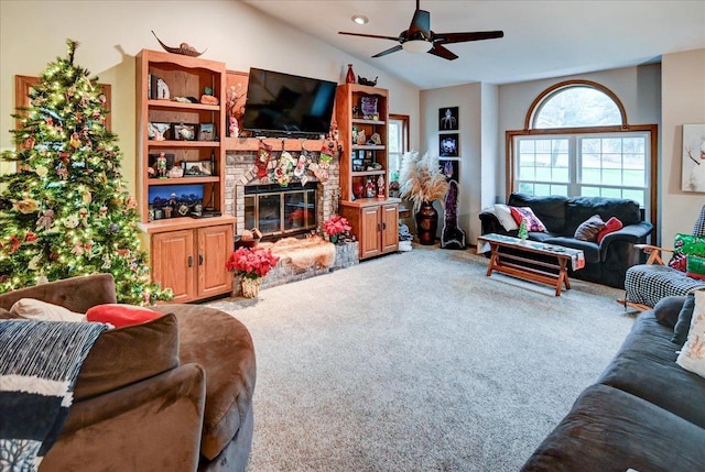 carpeted living room featuring a stone fireplace, ceiling fan, and lofted ceiling