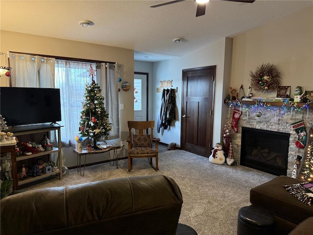 living room featuring ceiling fan, a fireplace, carpet floors, and a textured ceiling