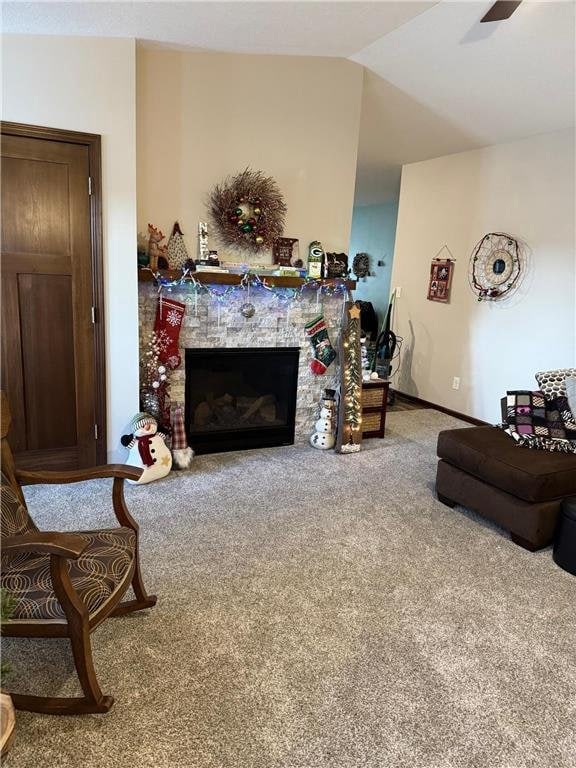 carpeted living room featuring a stone fireplace, ceiling fan, and vaulted ceiling