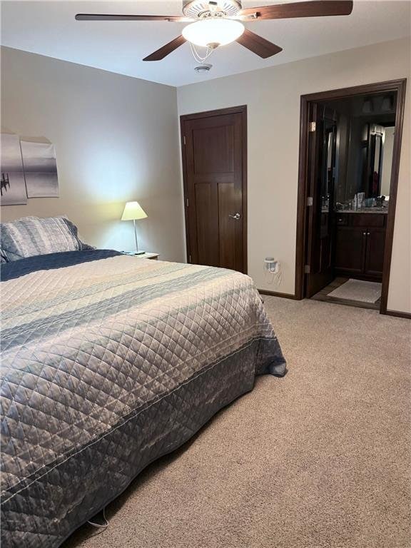 bedroom with connected bathroom, ceiling fan, and light carpet