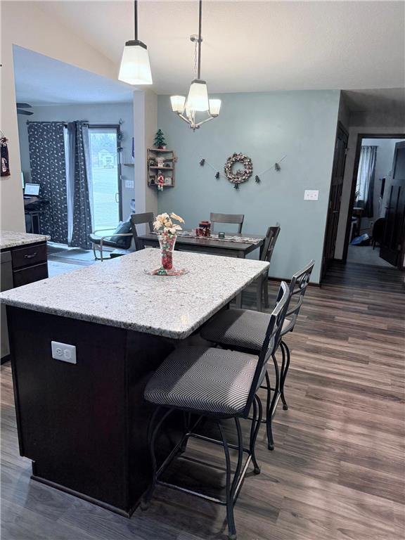 kitchen with a center island, hanging light fixtures, black dishwasher, dark hardwood / wood-style flooring, and a breakfast bar area