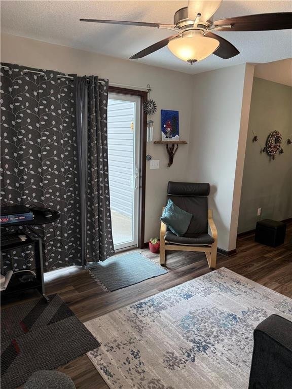 living area with a textured ceiling, ceiling fan, and dark hardwood / wood-style floors