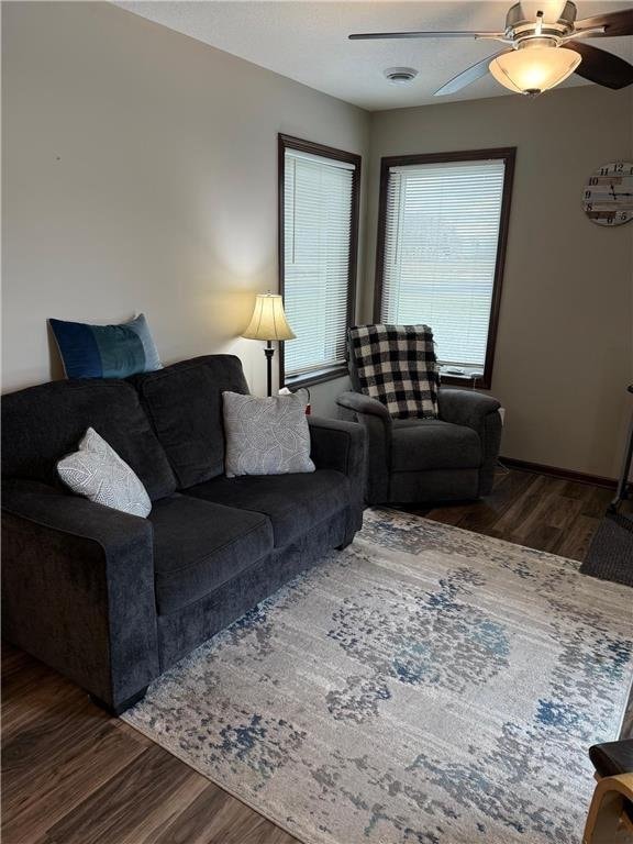 living room featuring ceiling fan and dark hardwood / wood-style flooring