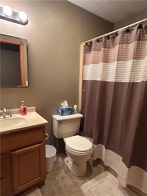 bathroom with walk in shower, vanity, a textured ceiling, and toilet