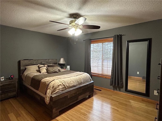 bedroom with ceiling fan, a textured ceiling, and light wood-type flooring