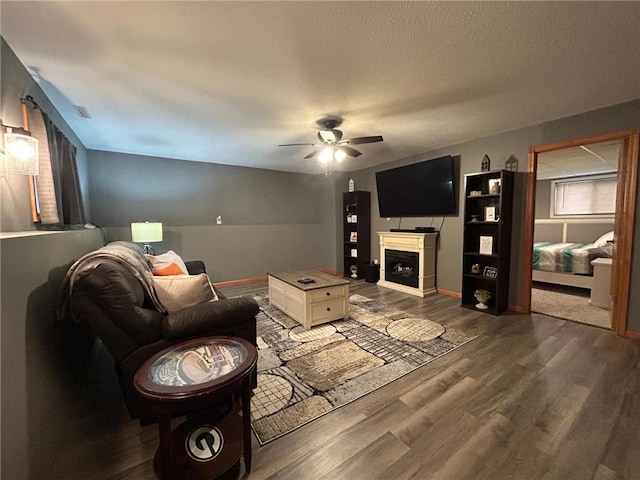 living room with ceiling fan, a textured ceiling, and hardwood / wood-style flooring