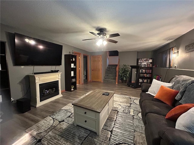 living room with ceiling fan, hardwood / wood-style floors, and a textured ceiling