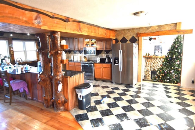 kitchen featuring ceiling fan, sink, a stone fireplace, a breakfast bar, and appliances with stainless steel finishes