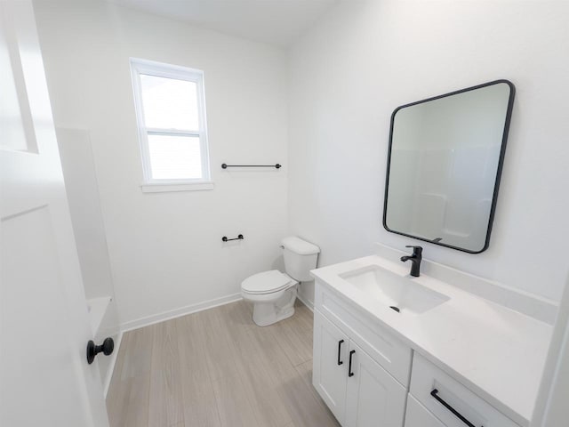 full bath featuring walk in shower, baseboards, toilet, wood finished floors, and vanity