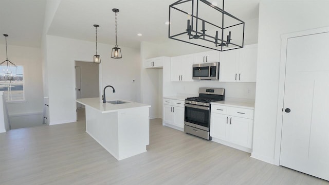 kitchen with a sink, stainless steel appliances, white cabinets, and light countertops