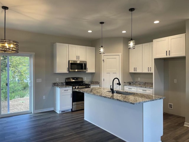 kitchen with light stone counters, appliances with stainless steel finishes, white cabinetry, and a sink