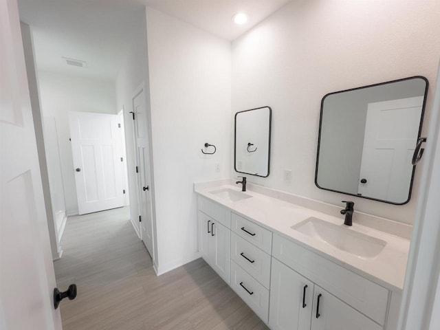 full bathroom with double vanity, wood finished floors, visible vents, and a sink