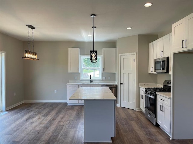 kitchen with a center island, appliances with stainless steel finishes, dark wood-style floors, white cabinets, and a sink