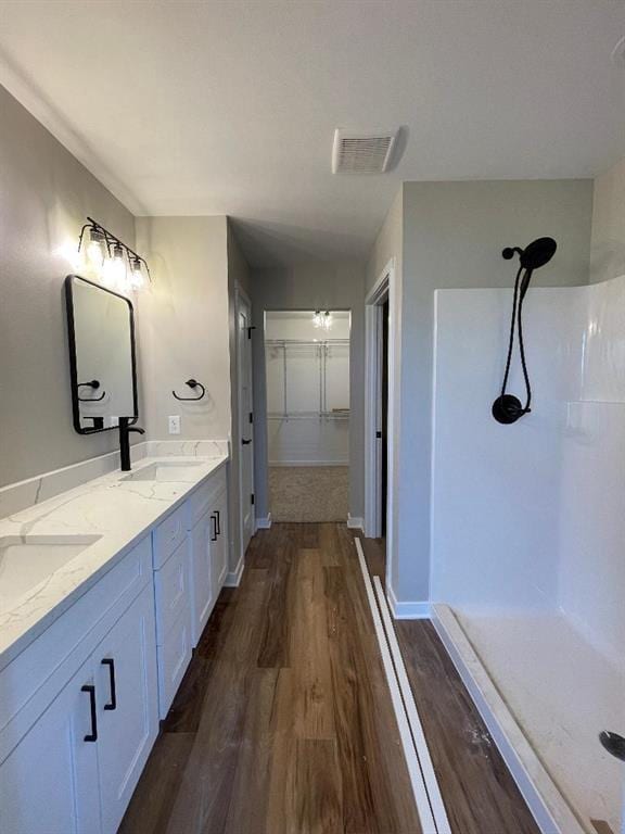 bathroom with hardwood / wood-style flooring, vanity, and walk in shower