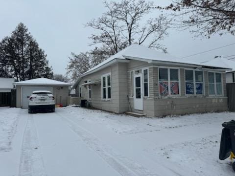 view of snow covered exterior featuring an outbuilding and a garage