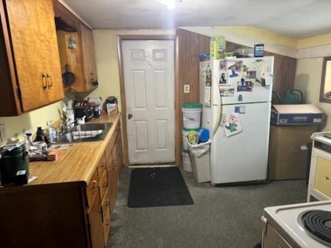 kitchen featuring dark colored carpet, sink, and white refrigerator