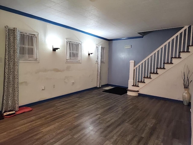 basement with dark wood-type flooring and crown molding