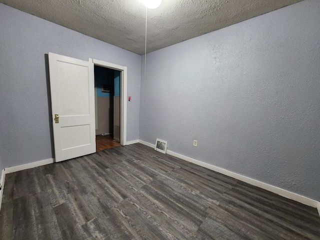 empty room with dark hardwood / wood-style flooring and a textured ceiling