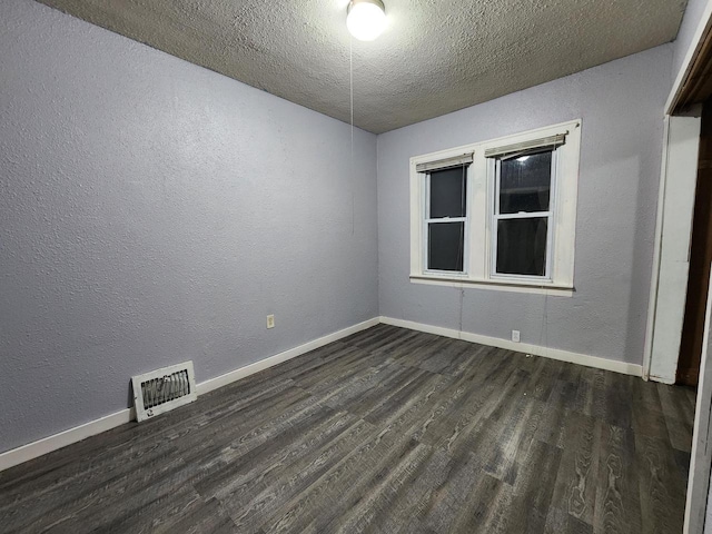 spare room featuring dark hardwood / wood-style floors and a textured ceiling