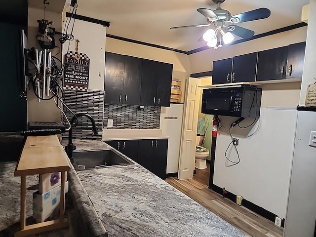 kitchen with decorative backsplash, light hardwood / wood-style floors, ceiling fan, and sink