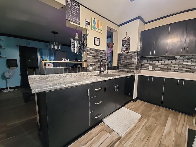 kitchen with pendant lighting, sink, decorative backsplash, light hardwood / wood-style floors, and kitchen peninsula