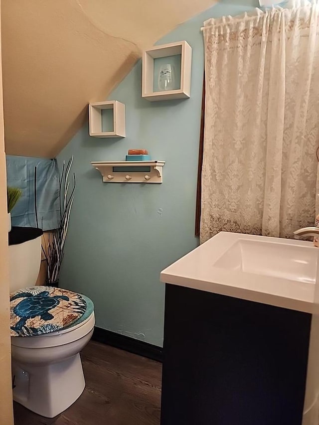 bathroom with hardwood / wood-style floors, vanity, toilet, and lofted ceiling