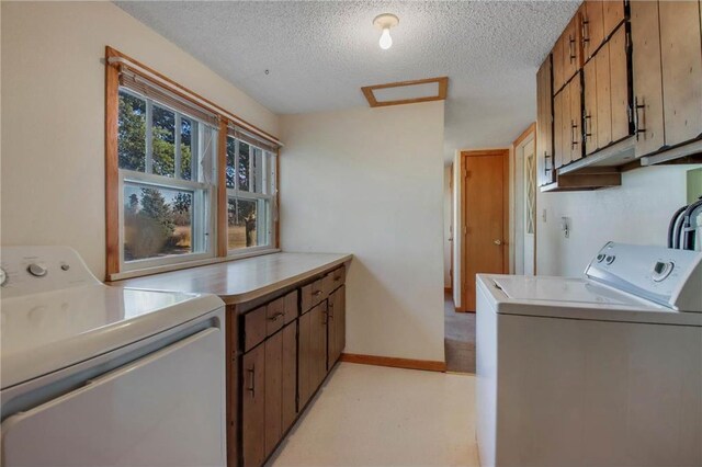 washroom with washing machine and clothes dryer, cabinets, and a textured ceiling