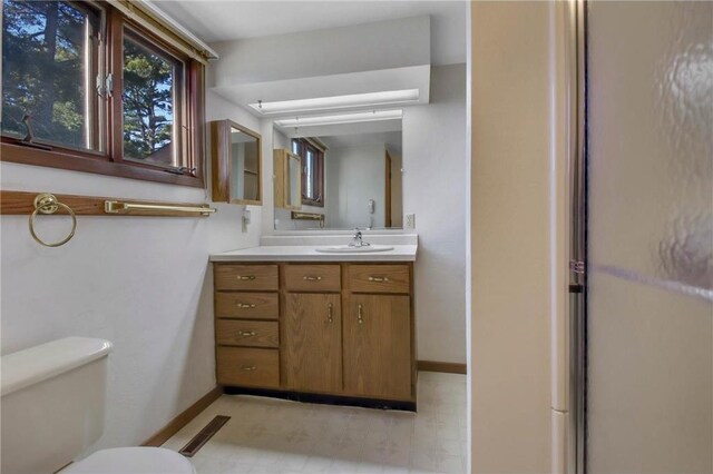 bathroom with a shower with door, vanity, and toilet