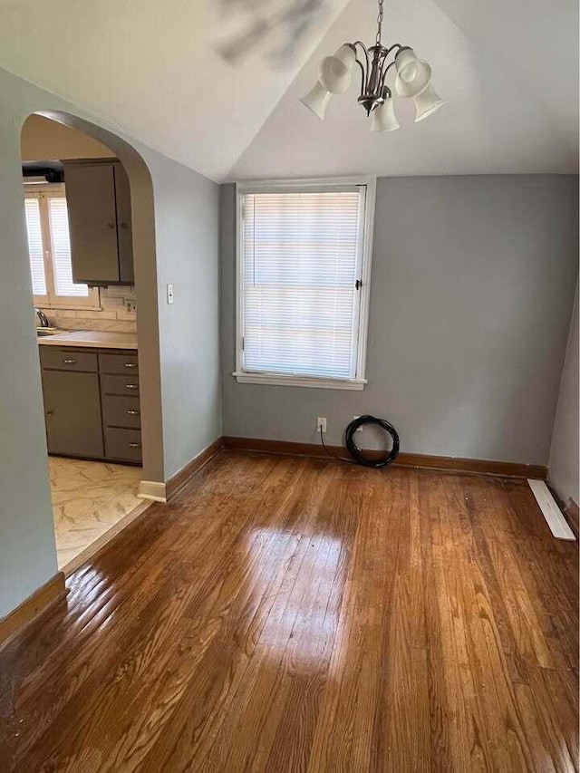 unfurnished dining area featuring a chandelier, light hardwood / wood-style floors, vaulted ceiling, and sink