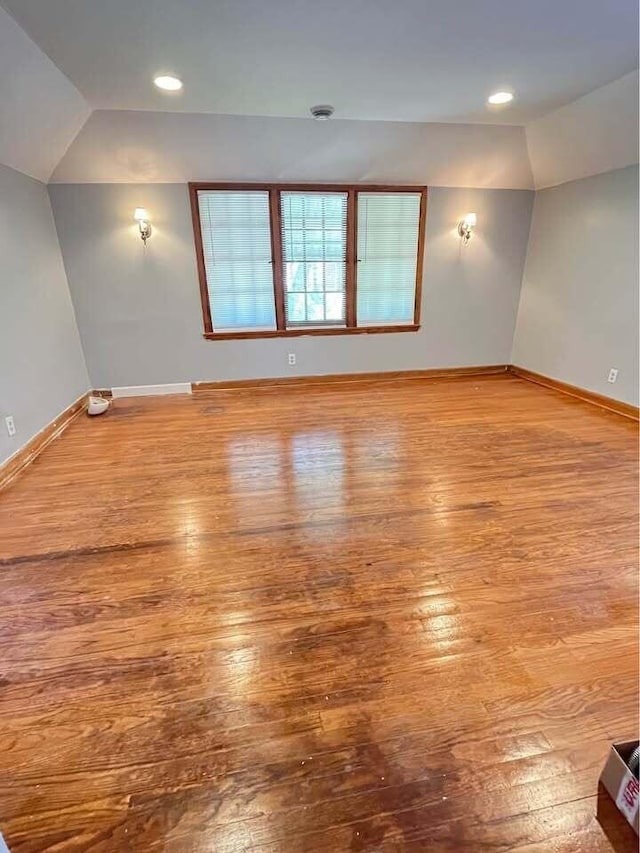 unfurnished room with lofted ceiling and hardwood / wood-style flooring