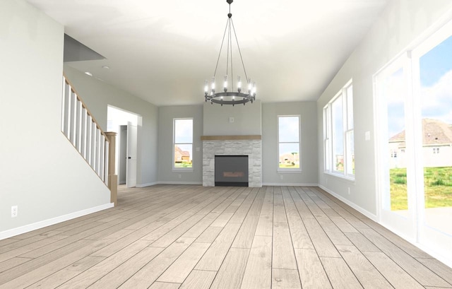 unfurnished living room with a notable chandelier, plenty of natural light, and light wood-type flooring