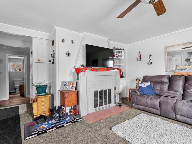 living room with carpet flooring, ceiling fan, crown molding, and a brick fireplace