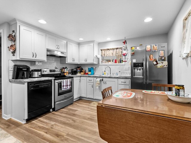 kitchen featuring appliances with stainless steel finishes, backsplash, sink, light hardwood / wood-style flooring, and white cabinets