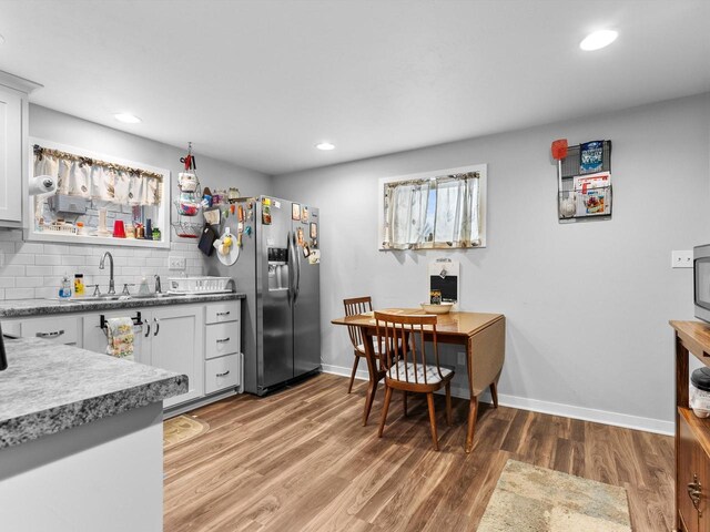 kitchen featuring hardwood / wood-style floors, white cabinets, sink, stainless steel refrigerator with ice dispenser, and tasteful backsplash