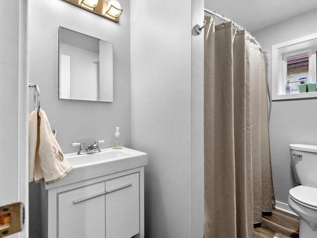 bathroom with a shower with curtain, vanity, hardwood / wood-style flooring, and toilet