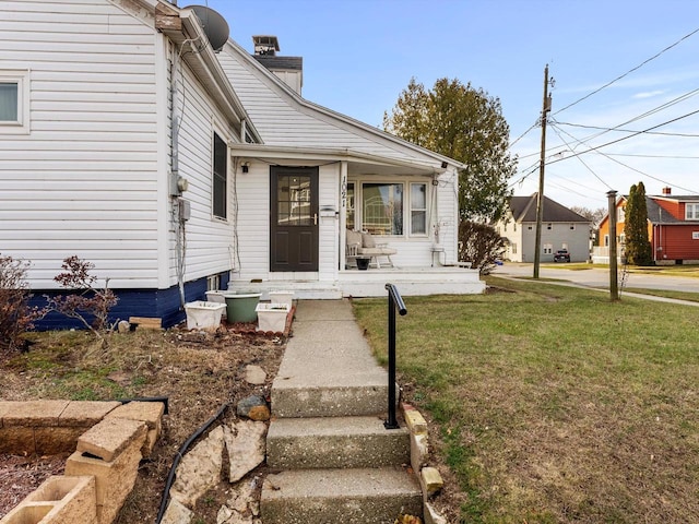 view of exterior entry with covered porch and a yard