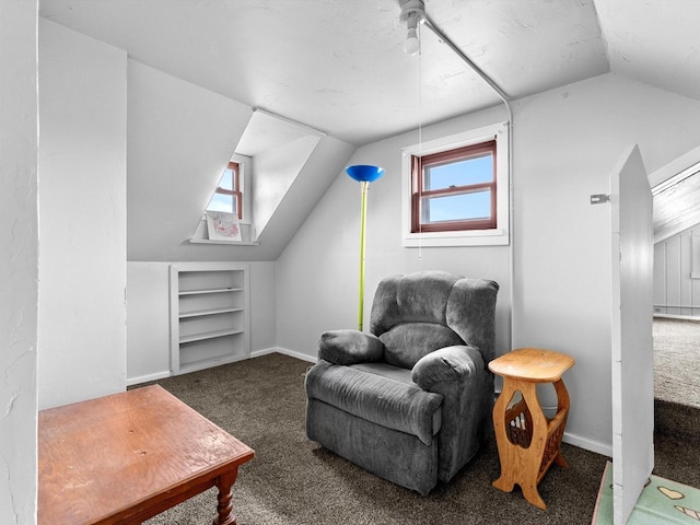 living area featuring carpet flooring, built in shelves, and lofted ceiling