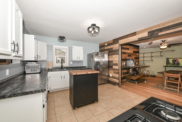 kitchen with ceiling fan, a kitchen island, stainless steel refrigerator with ice dispenser, decorative backsplash, and white cabinets