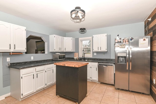 kitchen featuring a center island, white cabinets, sink, light tile patterned floors, and stainless steel appliances