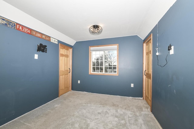 empty room featuring light colored carpet and lofted ceiling