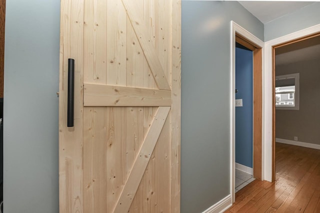 corridor with a barn door and wood-type flooring