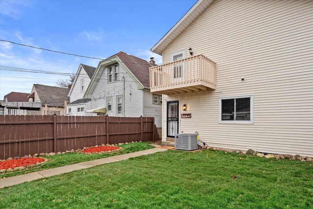 rear view of house featuring a yard, a balcony, and central air condition unit