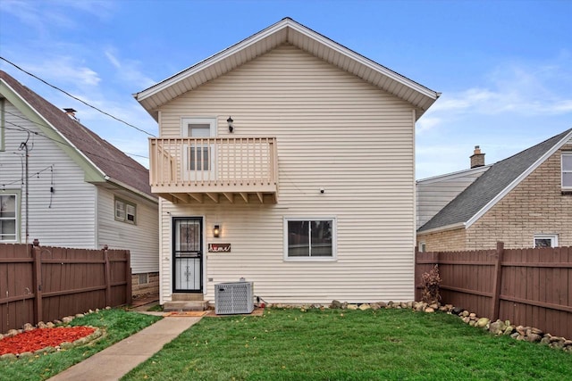 rear view of house featuring a yard, a balcony, and central AC