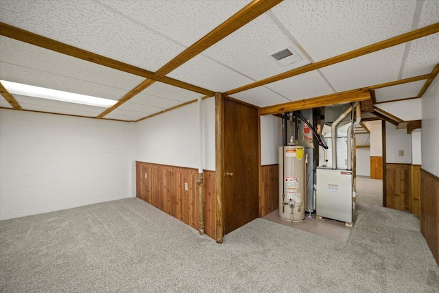 basement with carpet floors, gas water heater, heating unit, and wood walls