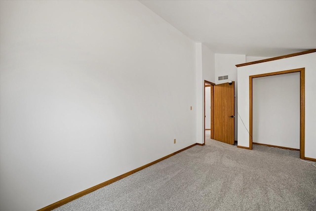 unfurnished bedroom with light carpet, a closet, and vaulted ceiling